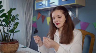 Beyaz gömlekli güzel bir kızın yakın çekimi boncuk süsleme oluşturur. Kız boncuk bir dekorasyon yarattı. El yapımı iş