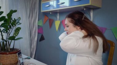 Beyaz gömlekli güzel bir kızın yakın çekimi boncuk süsleme oluşturur. Bir kız kendi elleriyle yapılmış boncuklu bir mücevheri deniyor. El yapımı iş