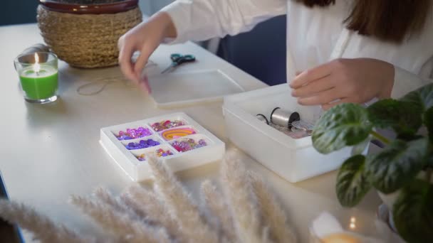 Un primer plano de una hermosa chica con una camisa blanca crea una decoración de cuentas. Trabajo hecho a mano — Vídeo de stock