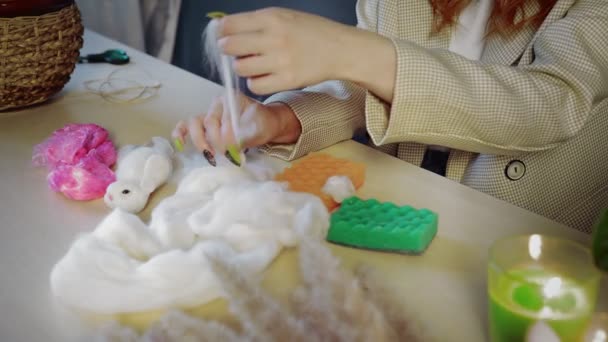 Close-up of a beautiful red-haired girl, she rolls wool and creates toys. Handmade work — Stock Video