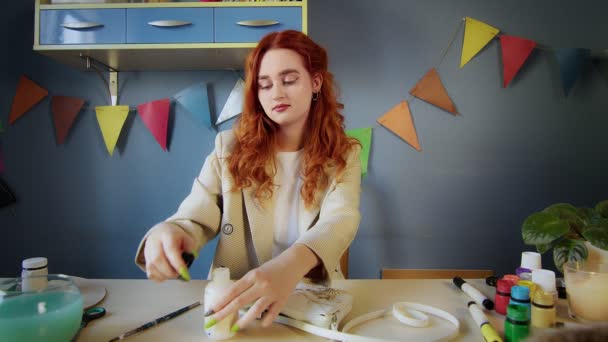 El plan general de una hermosa chica pelirroja dibujando con pinturas multicolores en una bolsa. Trabajo hecho a mano — Vídeos de Stock