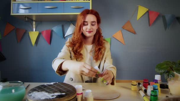 A beautiful red-haired girl artist mixes paints on a palette. Art — Stock Video
