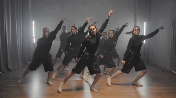 Un grupo de hermosas chicas bailando en el interior en trajes negros. Bailes — Foto de Stock