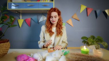 Güzel kızıl saçlı bir kızın genel planı yün sarıp oyuncak yapmaktır. El yapımı iş