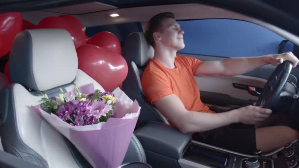 Un ragazzo felice cavalca in macchina con un mazzo di fiori. Regali — Video Stock