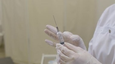 Enjeksiyon aşısı için aşı hazırlayan kadın bir doktorun ellerini yakın plan çekin.