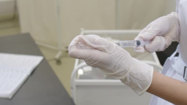 Enjeksiyon aşısı için aşı hazırlayan kadın bir doktorun ellerini yakın plan çekin. — Stok video
