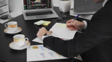 Bir dergiye bilgi yazan erkeklerin yakın çekimi. Ofiste çalışan bir iş adamı elle not alır..