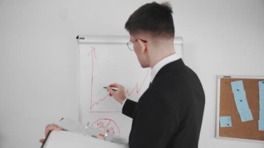 İş adamı, iş meselelerini çözer. Bir adam manyetik kartın başında durur ve grafikler çizer. İş adamları. Yakın plan.