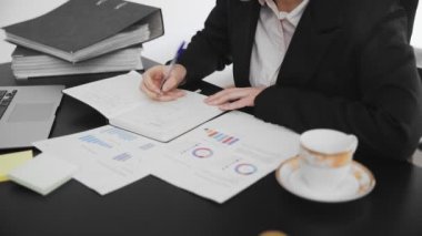 Bir dergiye bilgi yazan erkeklerin yakın çekimi. Ofiste çalışan bir iş adamı elle not alır..