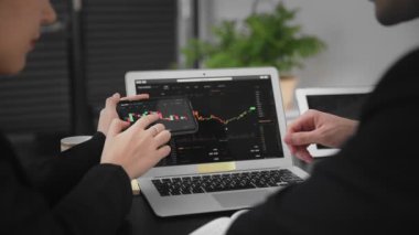 Bir iş adamı ve bir kadın masada oturmuş bilgisayardaki bitcoin istatistiklerini analiz ediyorlar. İş adamları. Yakın plan.