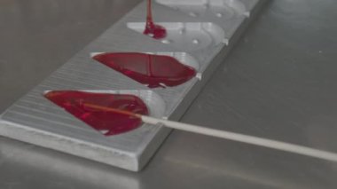 Karamel yuvarlak şekillere dökülüyor. Çubukta lolipop yapmak