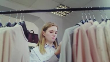 Şirin bir kız mağazadan kıyafet seçer. Alışveriş.