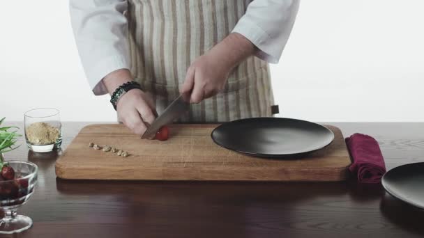 Mens händer skär jordgubbar på en träskiva med kniv — Stockvideo