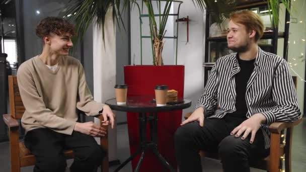 Twee homo 's op een date zitten in een koffieshop koffie te drinken en lachen. LGBT — Stockvideo