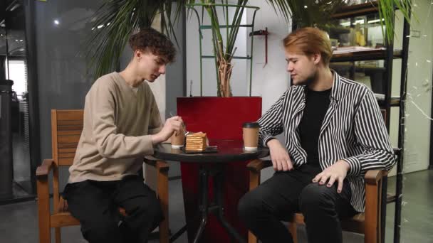 Dwóch gejów na randce siedzi w kawiarni, pije kawę i rozmawia. LGBT — Wideo stockowe