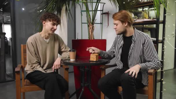 Dos gays en una cita están sentados en una cafetería, bebiendo café y charlando. LGTB — Vídeo de stock