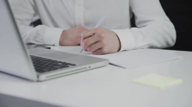 Tanınmayan bir adam kağıda not alır. Uzaktan kumanda. Serbest çalışıyorum. Video hareket halinde. Yakın plan.