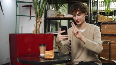 Kafede oturan ve telefonda videoyla konuşan bir adamın yakın çekimi. Kahve evi.