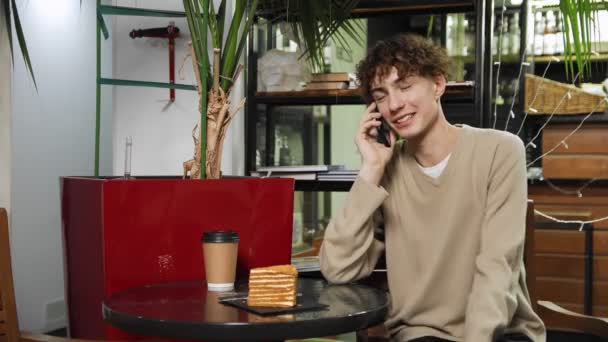 Bir kafede oturan ve telefonda konuşan bir adamın yakın çekimi. Kahve evi. — Stok video