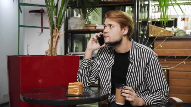 Κοντινό πλάνο ενός τύπου που κάθεται σε ένα καφέ και μιλάει στο τηλέφωνο. Καφετέρια — Αρχείο Βίντεο