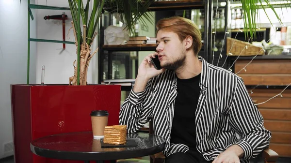 Primer plano de un tipo sentado en un café y hablando por teléfono. Cafetería — Foto de Stock