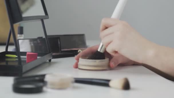 Salón de belleza en casa. Un primer plano de una mano femenina irreconocible aplicando polvo a un cepillo, maquillándose todos los días en casa — Vídeos de Stock
