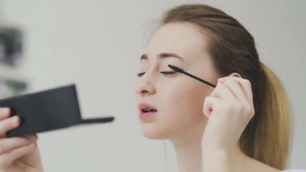 Make-up na tváři. Detailní záběr mladé ženy malování její dlouhé řasy s černou řasenkou. — Stock video