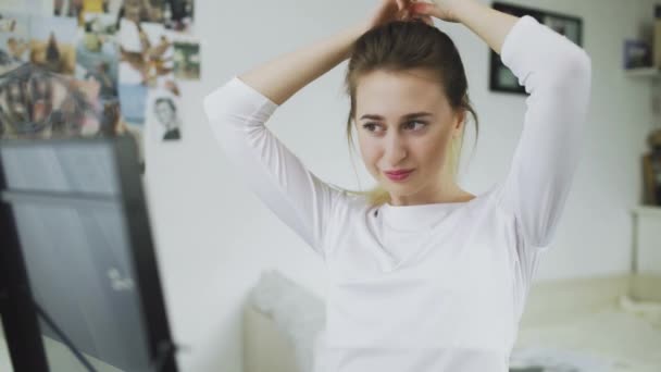 Красивая молодая женщина делает хвостик на голове перед зеркалом — стоковое видео