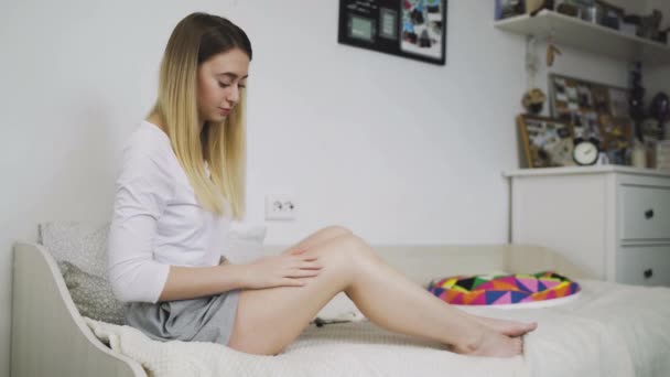 Koncept péče o tělo a krásy. Dívka rozmazává nohy hydratační krém pro péči, takže kůže je měkká a hedvábná. — Stock video