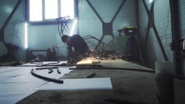 Bir adam dairesel testere ile çalışır. Sıcak metalden kıvılcımlar çıkıyor. Adam çelik üzerinde çok çalıştı..
