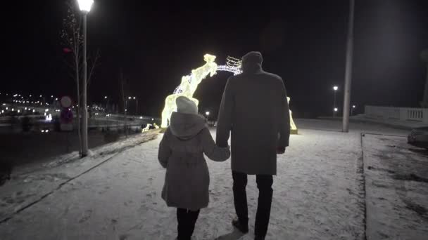 Egy férfi és egy lány télen szarvasokkal megy a fénylő boltívhez.. — Stock videók