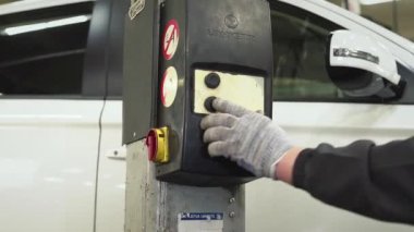 Araba tamircisi krikonun kaldırma ve taşıma mekanizmasındaki tuşa basarak arabayı indiriyor. Otomatik onarım, onarım, bakım