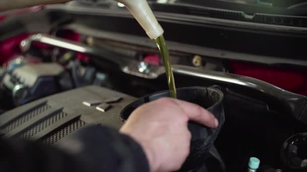 Ένας μηχανικός αυτοκινήτων αντικαθιστά το πετρέλαιο στον κινητήρα αυτοκινήτων. — Αρχείο Βίντεο