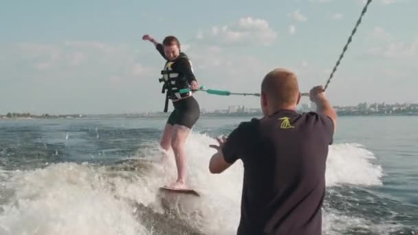 Ta holka je surfařka, jezdí na wakeboardu. Zkušený wakeboardista pomáhá dívce — Stock video
