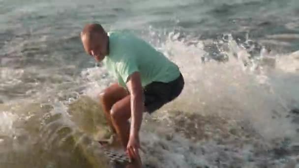 Un surfista saltando sobre un wakeboard. Un experimentado wakeboarder rocía agua en la cámara. — Vídeo de stock