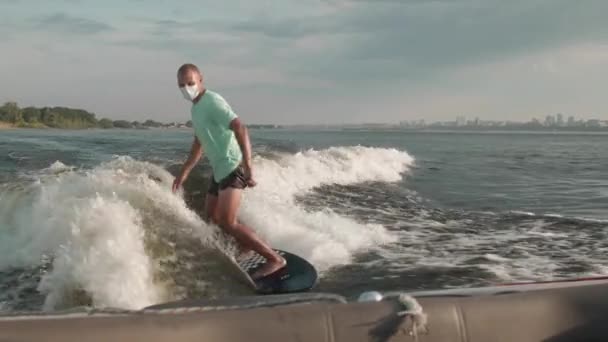 Ένας σέρφερ που πηδάει σε μια σανίδα με μάσκα. Ένας έμπειρος wakeboarder ρίχνει νερό σταγόνες στην κάμερα. — Αρχείο Βίντεο