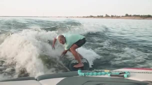 Ein Surfer springt auf einem Wakeboard. Ein erfahrener Wakeboarder sprüht Wassertropfen in die Kamera. — Stockvideo