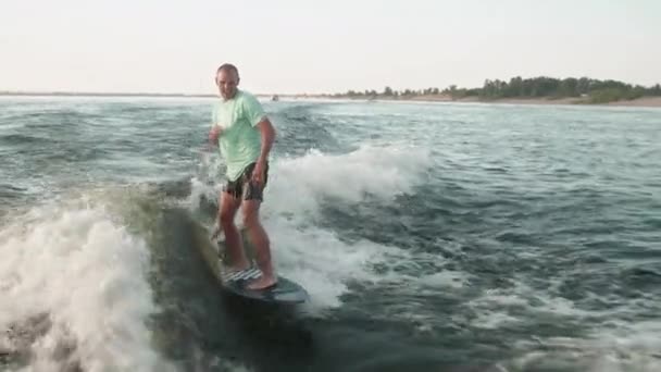 Un surfeur sautant sur un wakeboard. Un wakeboarder expérimenté pulvérise de l'eau dans la caméra. — Video