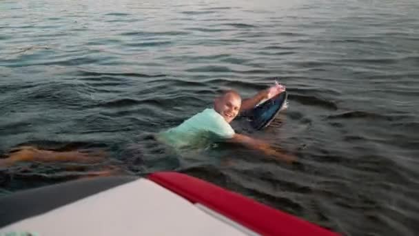 Um homem nada em um wakeboard e sorri — Vídeo de Stock