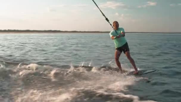 Ein Surfer springt auf einem Wakeboard. Ein erfahrener Wakeboarder sprüht Wassertropfen in die Kamera. — Stockvideo