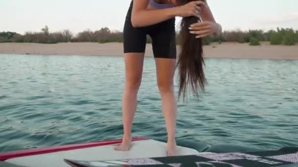 Žena stojí na motorovém člunu a sbírá si vlasy v culíku — Stock video