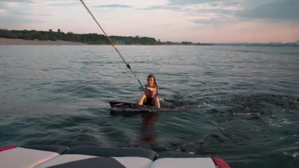 Una surfista saltando sobre un wakeboard. Un wakeboarder experimentado salpica el agua cae en la cámara. — Vídeo de stock