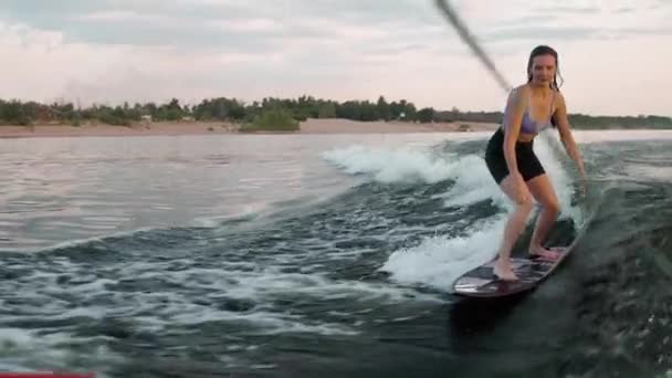 Μια γυναίκα σέρφερ που πηδάει σε μια σανίδα. Ένας έμπειρος wakeboarder ρίχνει νερό σταγόνες στην κάμερα. — Αρχείο Βίντεο
