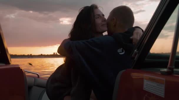 Парень и девушка обнимаются на закате, сидя в лодке. — стоковое видео