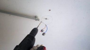 Erkek ellerine yakın çekim. Sondaj aleti. Metal kanca için tavana delik açmak için bir araç.