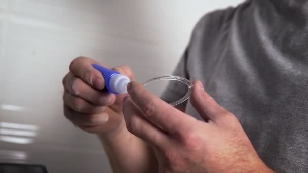 Eine Nahaufnahme der Hände eines nicht erkennbaren Mannes, der den Sockel für die Befestigung einer Deckenlampe mit Klebstoff klebt. Reparatur — Stockvideo
