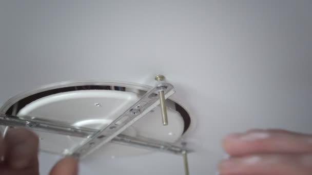 A close-up of the hands of an unrecognizable man inserting the base for mounting a ceiling light. Repair — Stock Video