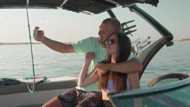 Ein Mann und eine Frau sitzen in einem Motorboot und fotografieren — Stockvideo