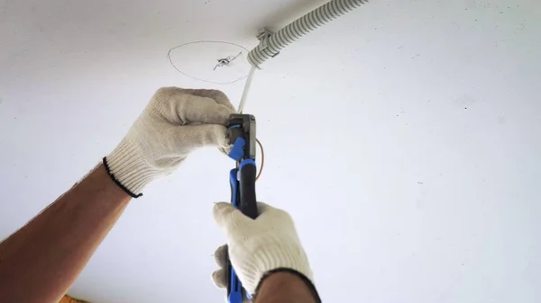 Un electricista masculino conectando una lámpara de techo a cables eléctricos en un nuevo edificio de apartamentos. Primer plano — Foto de Stock